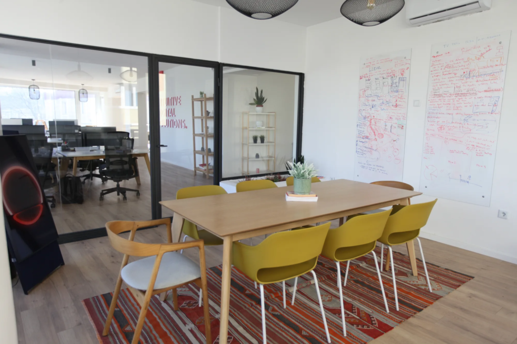 Sto za sastanke sa žutim stolicama na tradicionalnom tepihu, tabla u pozadini u Motiff coworking prostoru u Sarajevu