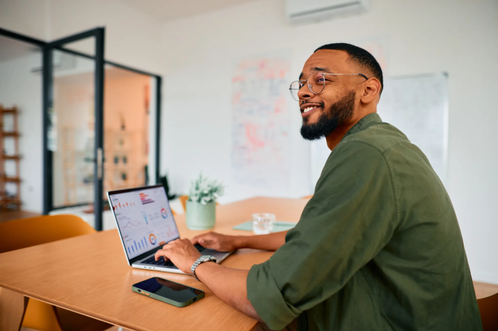 Smiling man working on a laptop at a meeting room desk in Motiff coworking space