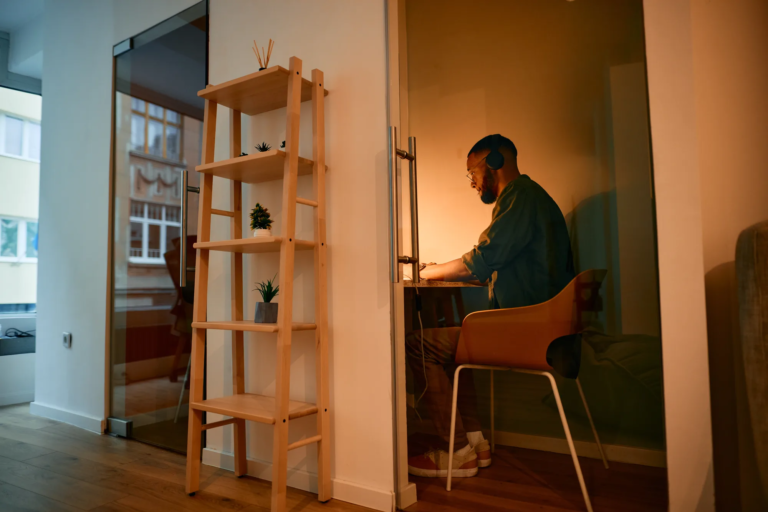 Man working focused in a phone booth at Motiff coworking space, wearing headphones
