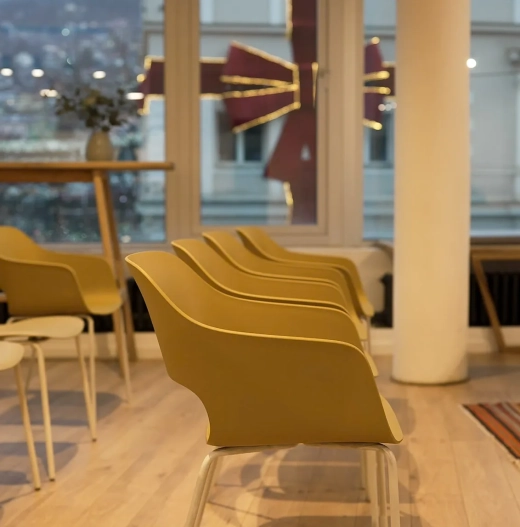 Row of mustard chairs by the window with mountain views at Motiff coworking space in Sarajevo
