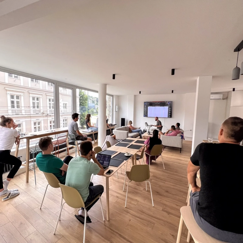 Team attending a workshop session with a presentation screen, large windows overlooking Sarajevo, at Motiff coworking space